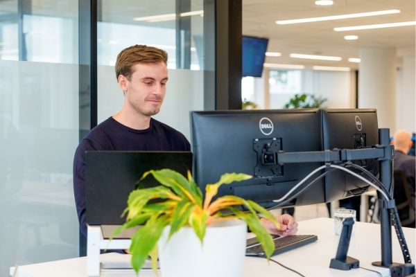 Man werkt op kantoor met dubbele monitor, bezig met SEO-content